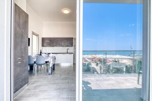 A modern kitchen with grey cabinets and a dining area with a table set for four. - Lanterne Luxury Apartments (Borghetto Santo Spirito)