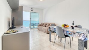 Un salon moderne avec un canapé, une table à manger et des chaises, un téléviseur et un balcon offrant une vue agréable.