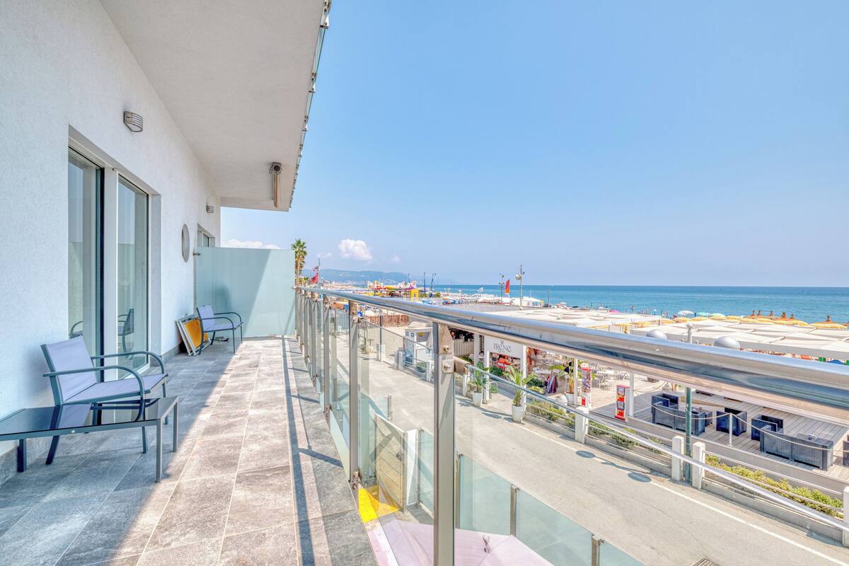 A balcony with a view of the beach and ocean.