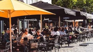 An outdoor café with outdoor seating, tables, and umbrellas. - Villa in Someren With Sauna Near Golf Course (Someren)
