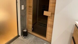 A hallway with a wooden door, a trash bin, and a tiled floor.