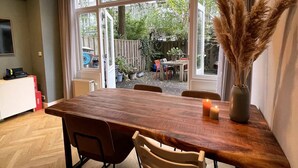 A dining area with a wooden table, chairs, and a vase of dried plants.