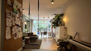 A spacious living area with a piano, a sofa, and a dining table.