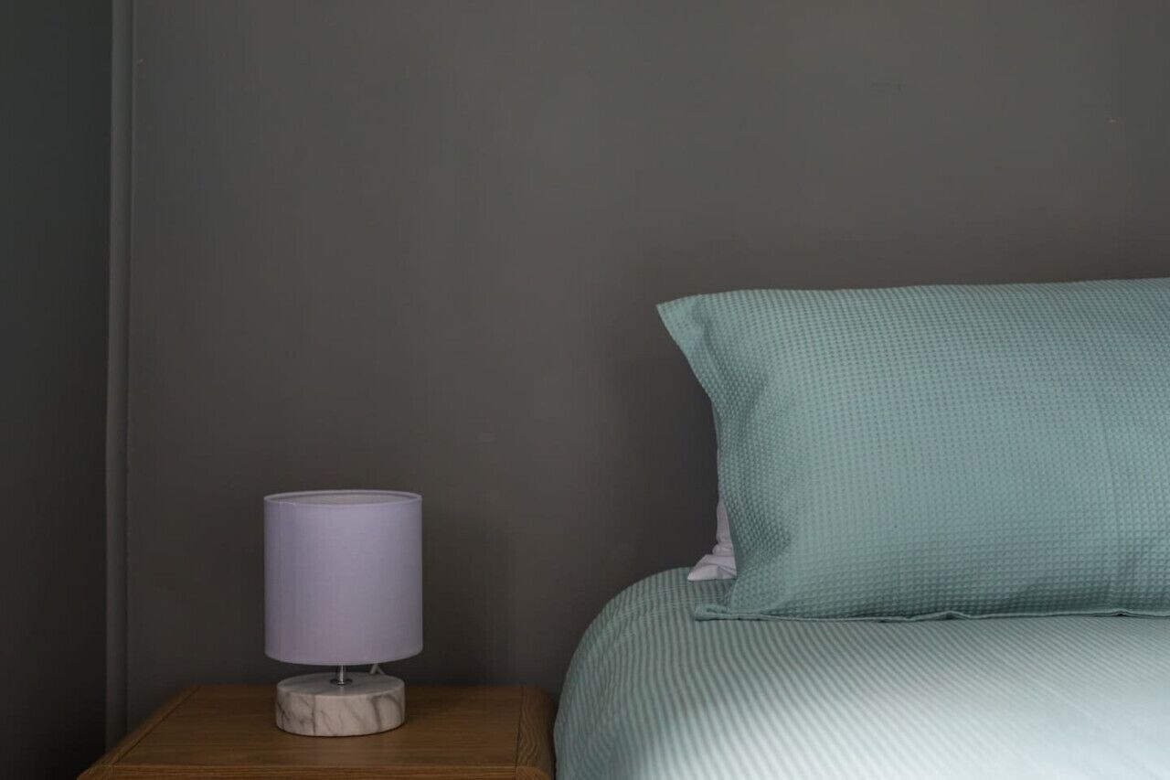 A bedroom with a bed, a nightstand, and a lamp.