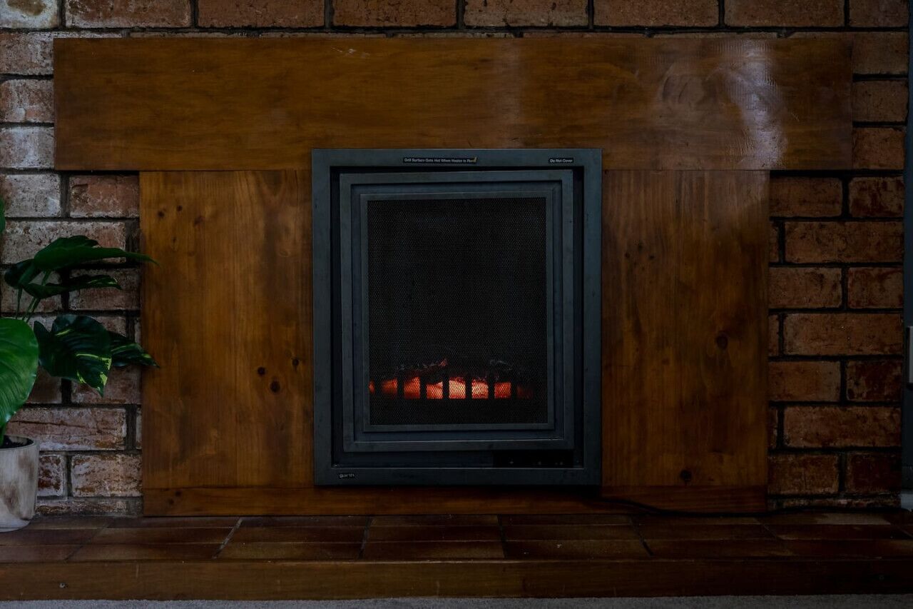 A fireplace with a wooden mantel and a metal screen.
