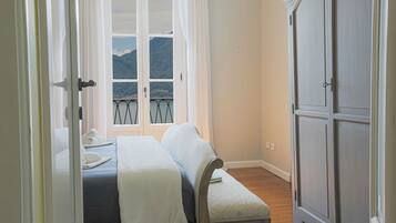 Una camera da letto con un letto, una panca, un armadio e una finestra vista montagne.