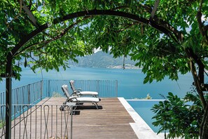 A wooden deck with two lounge chairs overlooking a body of water and a distant mountain. - La Wally - 4 Bedroom Villa with Pool & Lake View (Lombardia)