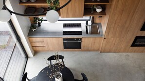 A modern kitchen with wooden cabinets, a stainless steel sink, and a dining area with a table and chairs. - Bendigo Lodges (Bendigo)