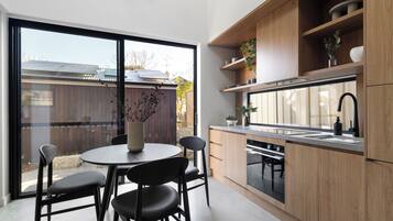 Una cocina moderna con un ventanal grande, armarios de madera y un comedor con mesa y sillas.