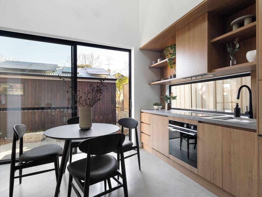 Una cocina moderna con un ventanal grande, armarios de madera y un comedor con mesa y sillas.