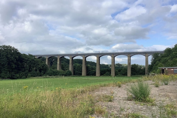 A viaduct over a green field with a clear sky.