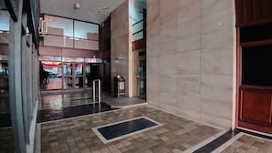 A spacious indoor area with a tiled floor, a reception desk, and a glass door leading to another section. - Tempo Corrientes (Córdoba)