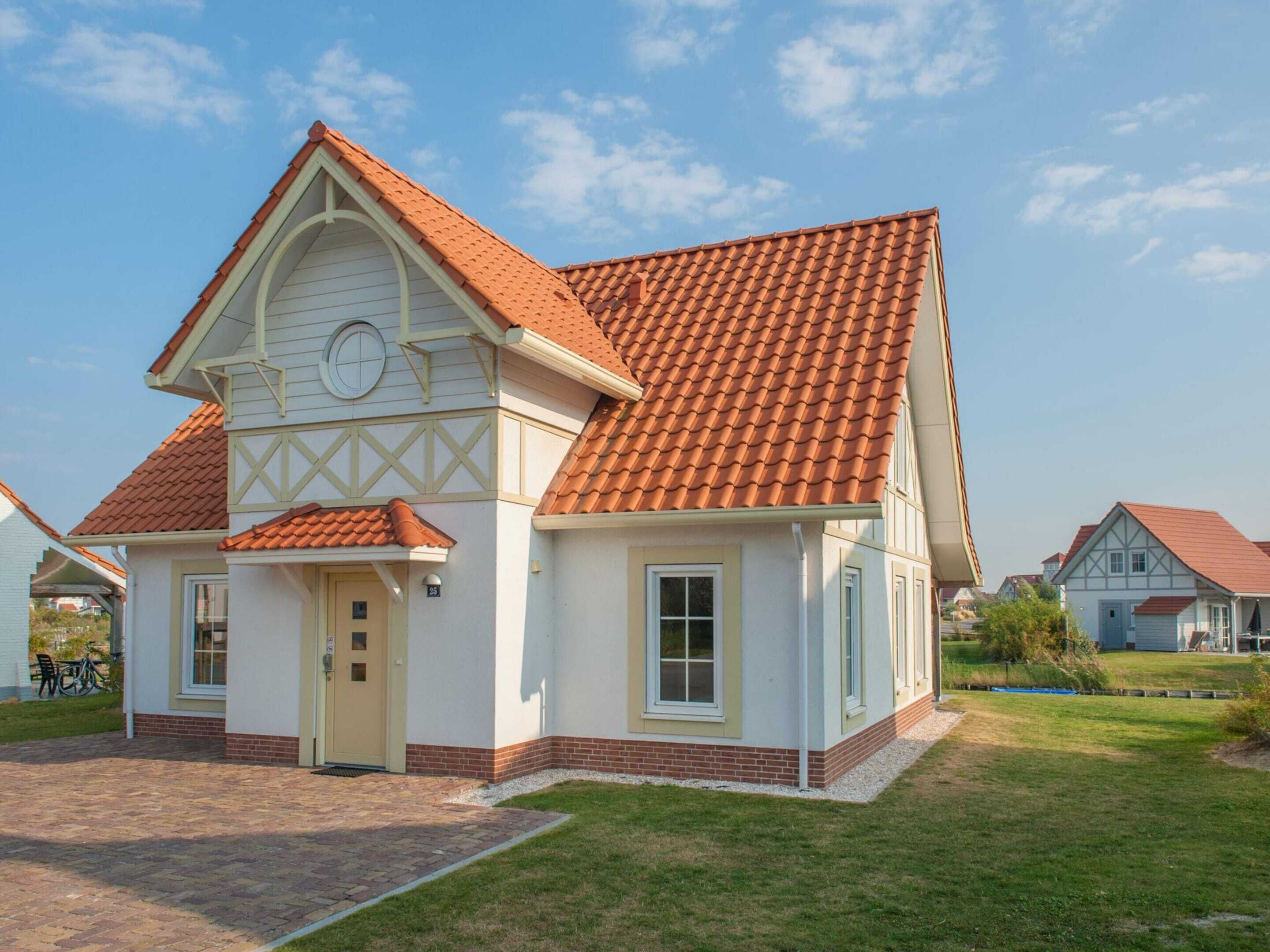 A two-story house with a red-tiled roof, white walls, and a small front porch.