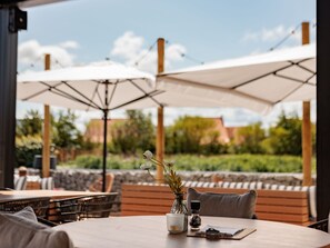 Enjoy a meal under the shade of two large umbrellas in a serene garden setting.
