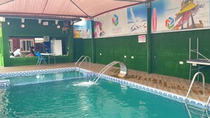Une piscine intérieure dotée d’un plongeoir, d’un espace de repos couvert et d’une fresque publicitaire pour des suites de glace.