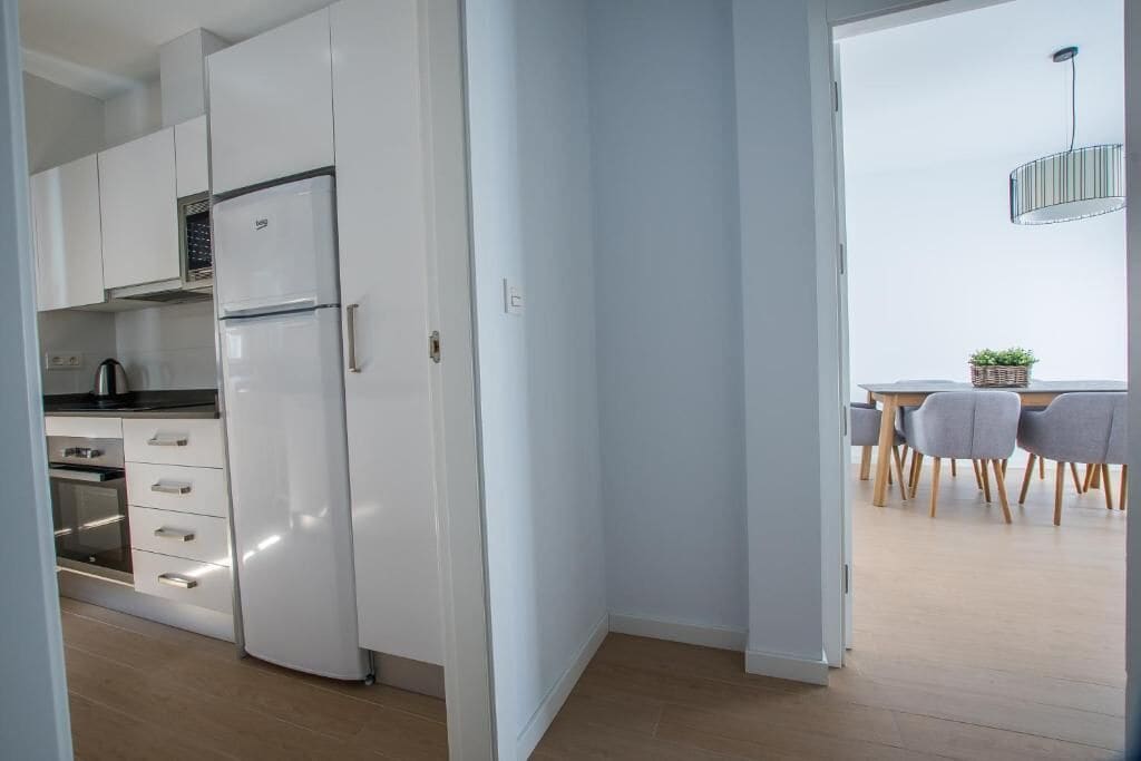 A modern kitchen with white cabinets, a built-in oven, and a refrigerator.