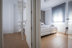 A modern bedroom with a bed, a wardrobe, and a window with blinds. - Ibericabeds Granada (Granada)