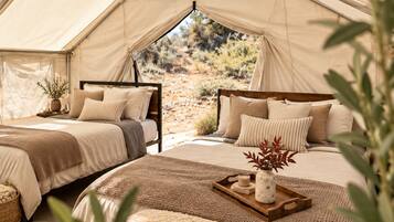 Acomodação em tenda com duas camas, um suporte com vela e vista para o exterior.