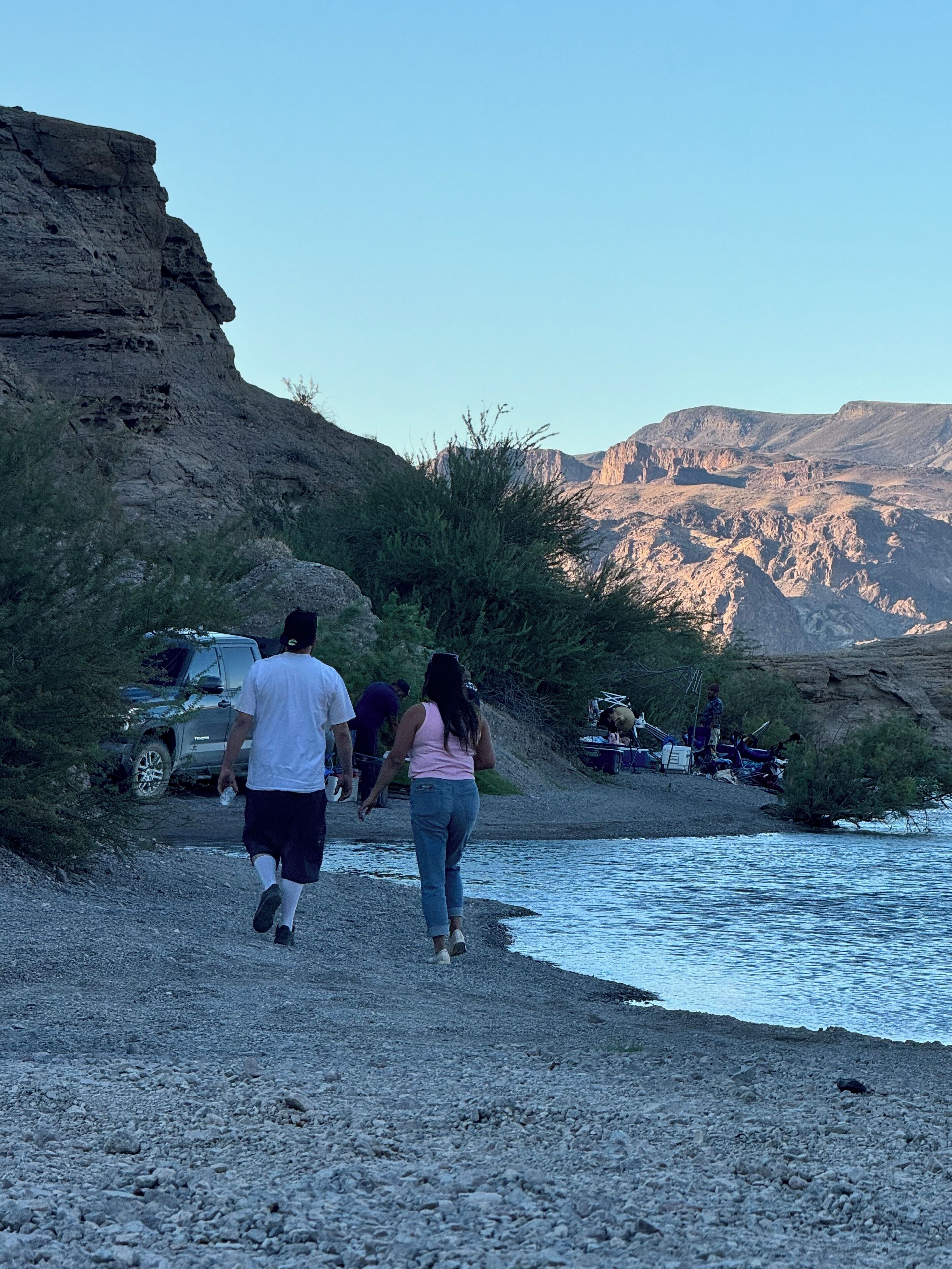 A rocky shoreline with a vehicle parked on the left.