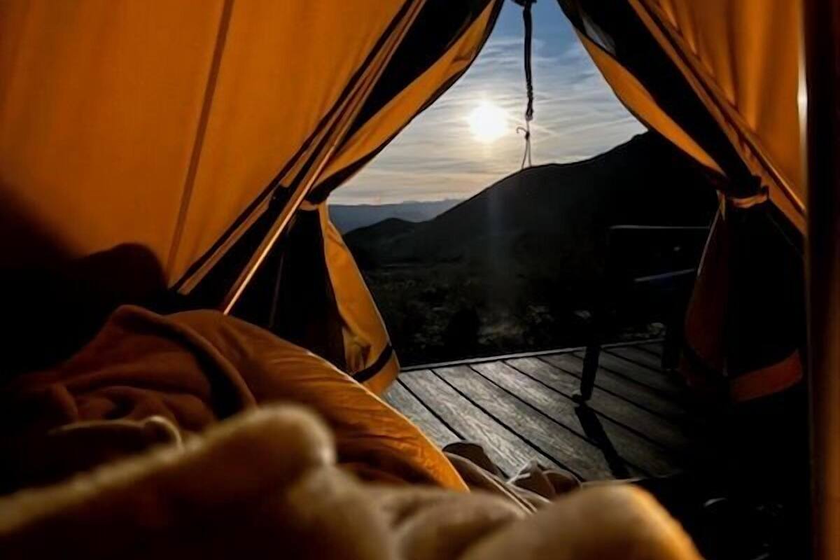 A tent with a view of the sunset and a wooden deck.