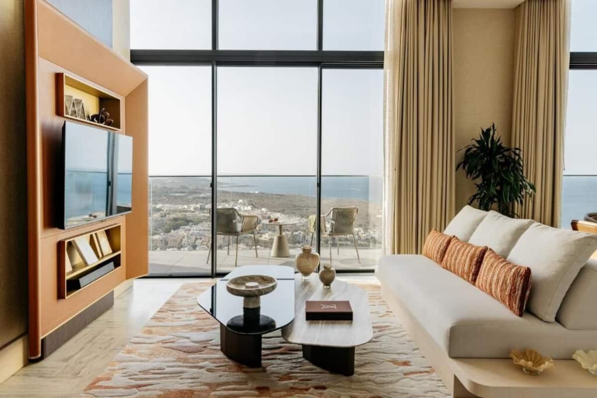 Una sala de estar moderna con un gran ventanal, un sofá, una mesa de centro y un mueble para la televisión.