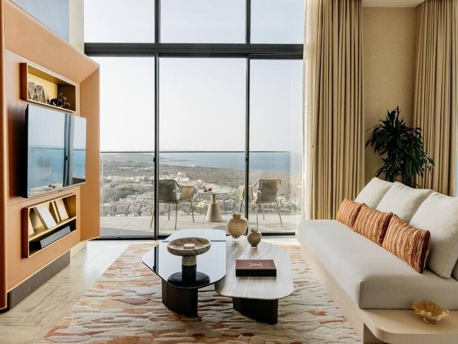 Una sala de estar moderna con un ventanal grande, un sofá, una mesa de centro y un mueble para la televisión.