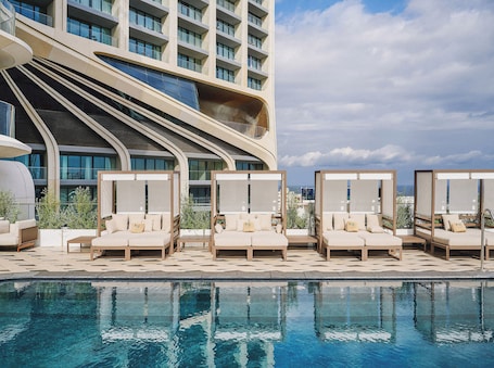 Una piscina techada, una piscina al aire libre, sombrillas