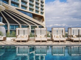 Una piscina techada, una piscina al aire libre, sombrillas