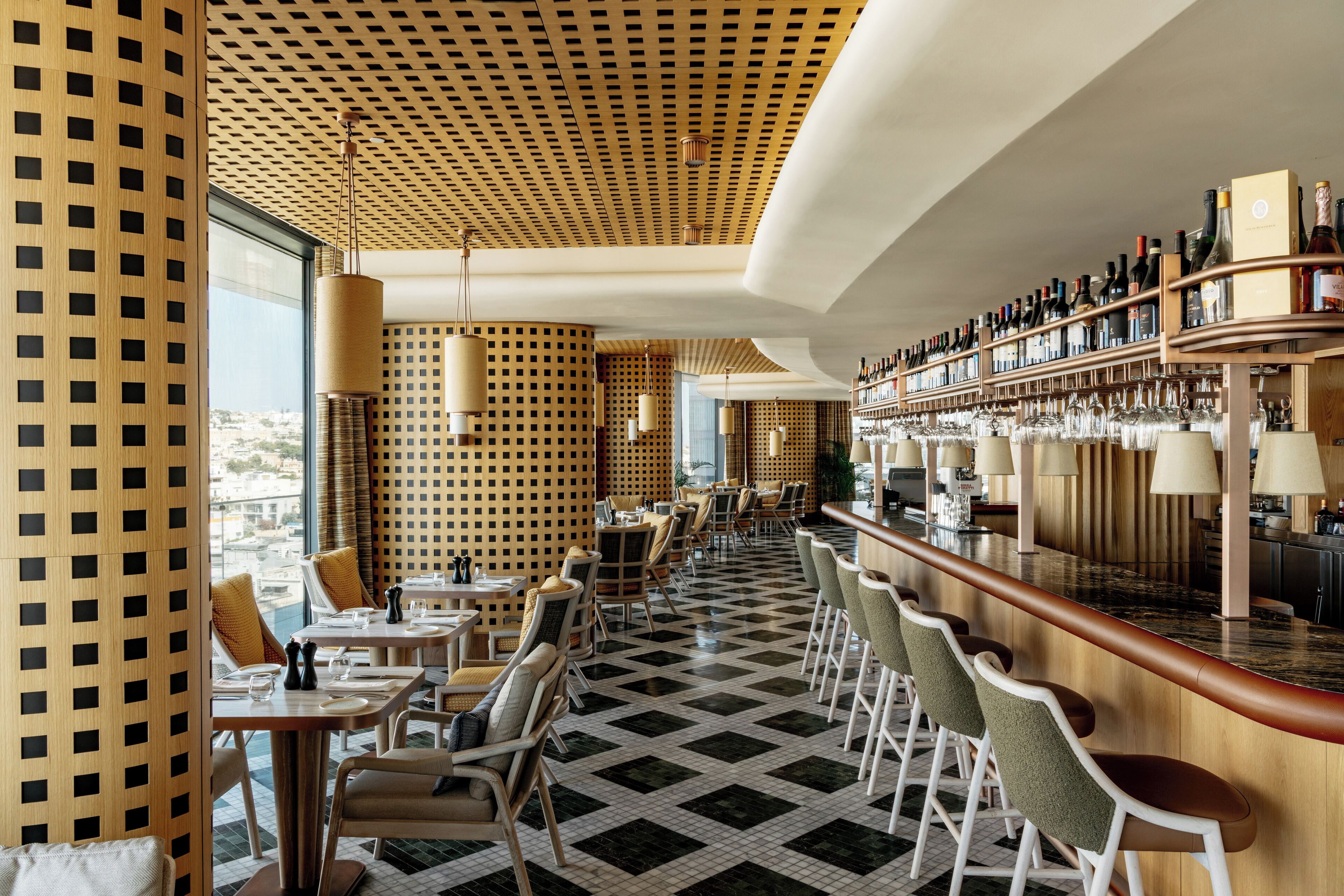 A modern bar area with a checkered floor, wooden paneling, and a variety of seating options.