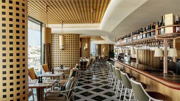A modern bar area with a checkered floor, wooden paneling, and a variety of seating options.