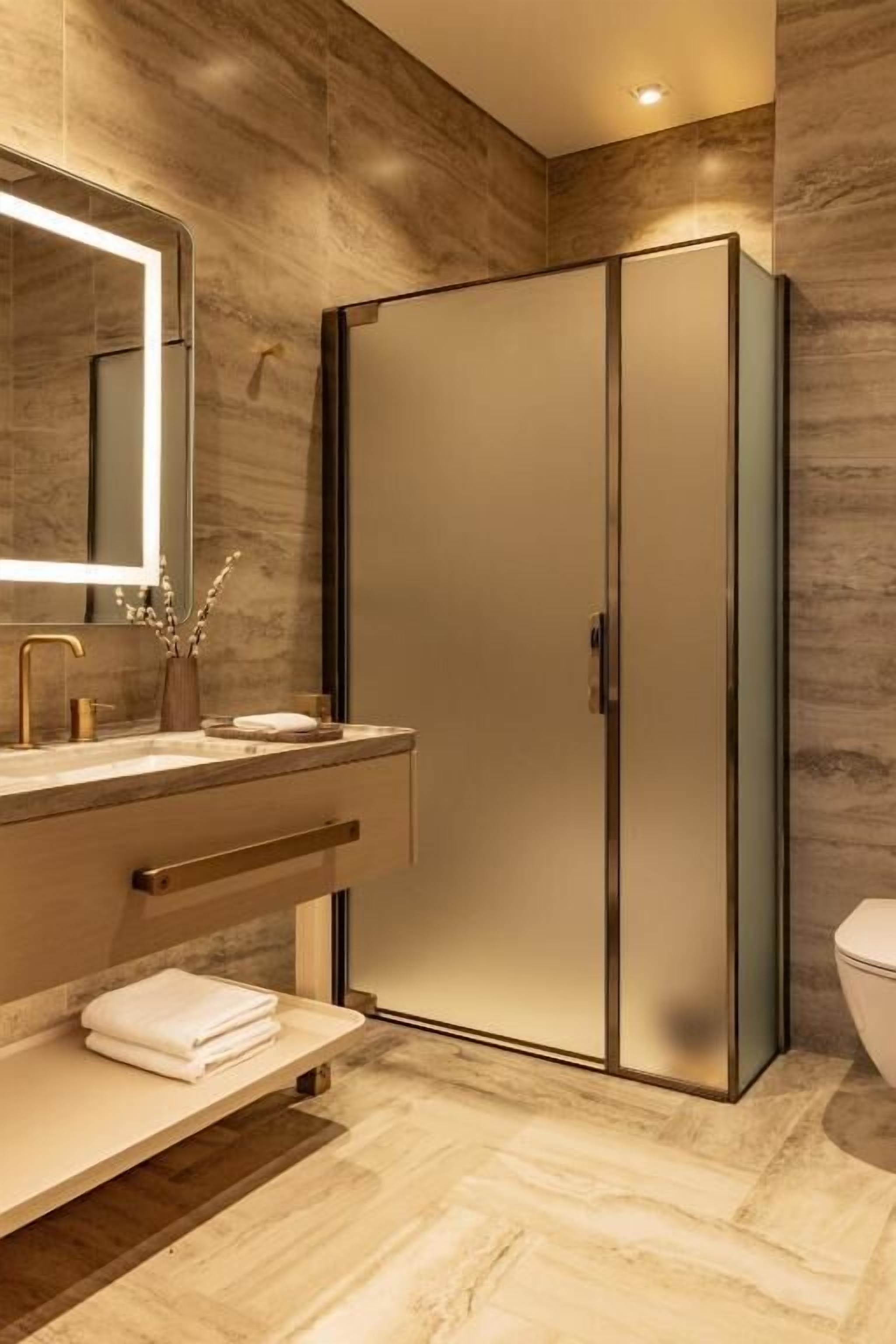 A modern bathroom with a large mirror, a sink, and a toilet.