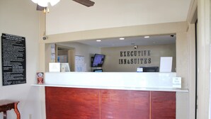 A reception desk with a sign reading "EXECUTIVE INN&SUITES" and a "NO PETS ALLOWED" sign.