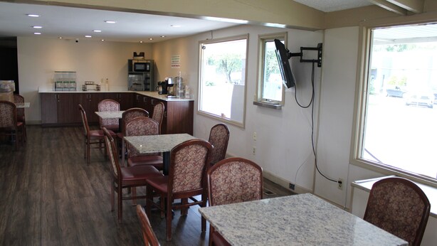 A restaurant with a counter, tables, and chairs.