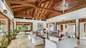 A spacious living area with white sofas, a glass coffee table, and wooden beams on the ceiling. - Gorgeous Villa at Casa de Campo With Large Pool Chef Maid and 2 Golf Carts (La Romana)