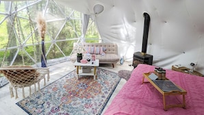 Ein gemütliches Zeltinnere mit einer Couch, einem Couchtisch, einem Teppich und einem Holztisch mit einem Laptop.