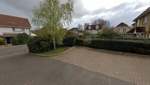 Una calle residencial con casas, un camino de entrada pavimentado y un árbol.