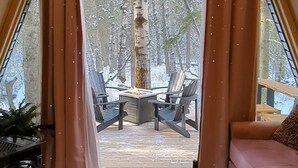 A cozy room with a large window, a fireplace, a round wooden table, and a sofa. - The Fern A-frame Cabin (Alberta Beach)