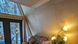 A cozy room with a sofa, a small round table, and a lamp. - The Fern A-frame Cabin (Alberta Beach)