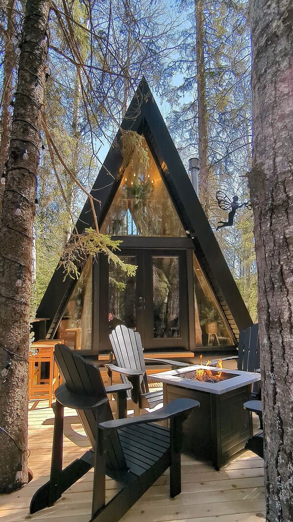Een chalet met een puntdak, houten terras en een zitgedeelte buiten.