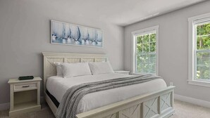 Une chambre à coucher avec un lit, une table de chevet et une fenêtre donnant sur un paysage verdoyant.
