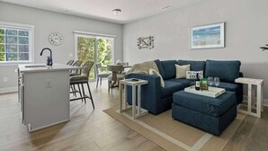 Un salon moderne comprenant un canapé, une table basse et un coin cuisine avec un évier et un plan de travail.