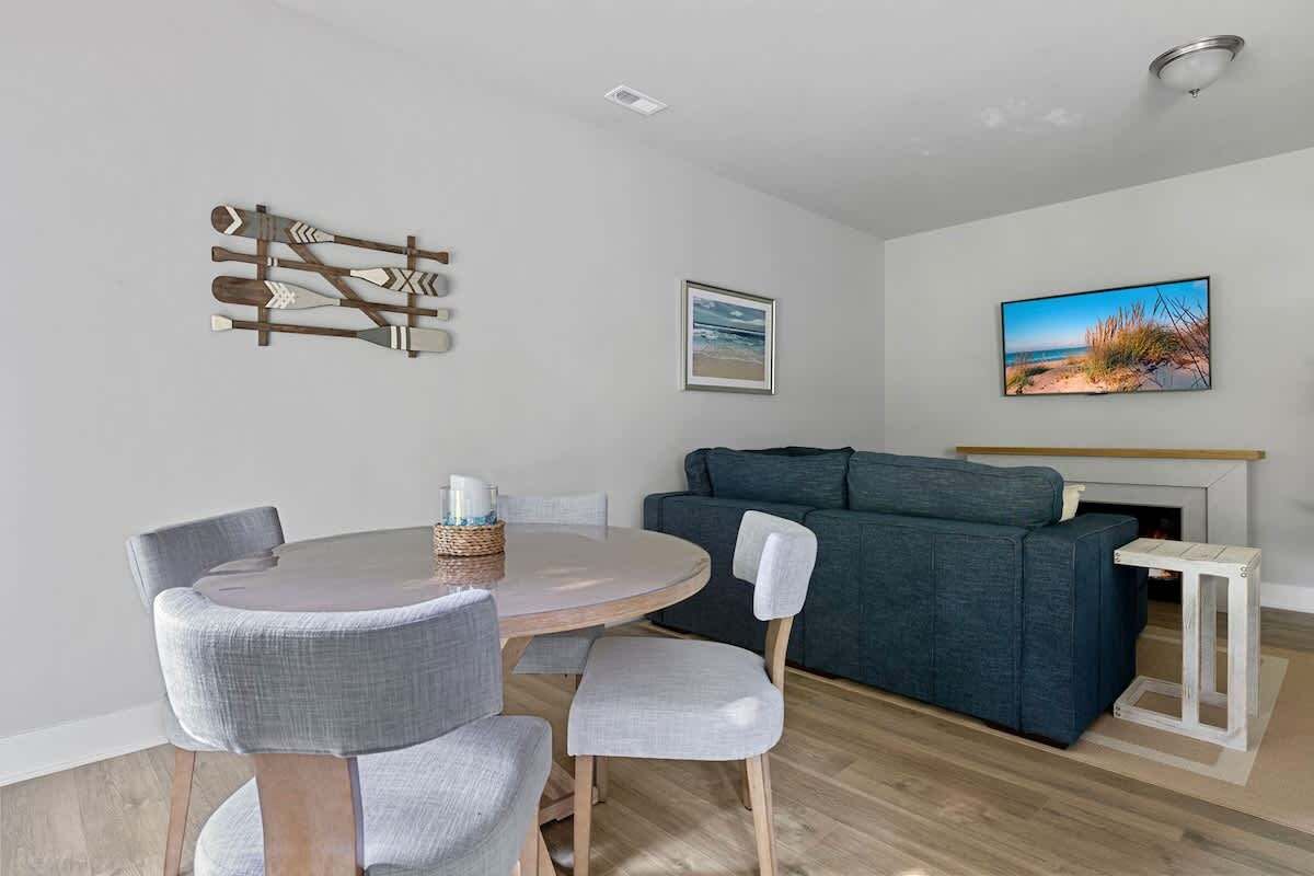 A living room with a round table, grey chairs, a blue sofa, and a fireplace.