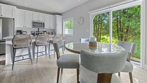 Une cuisine moderne avec des meubles blancs, un four à micro-ondes et un coin repas comprenant une table ronde et des chaises.