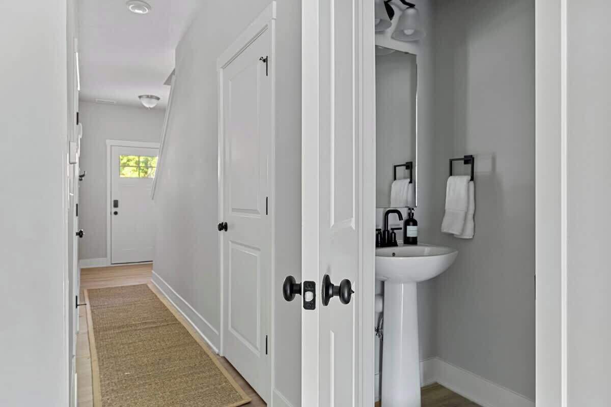A hallway with white doors, a white sink, and a towel rack.