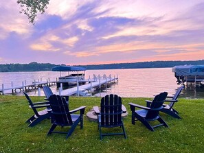 A lakeside view with chairs and a dock.