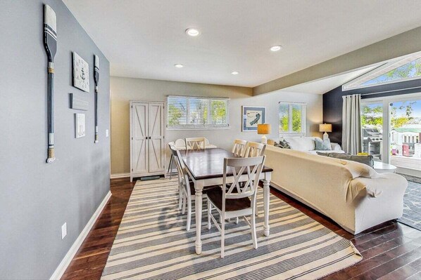 A modern living room with a dining area, a sofa, a coffee table, and a large window with a view.