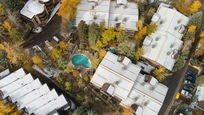 Una vista aerea di una zona residenziale con diverse case, una piscina e alberi circostanti.