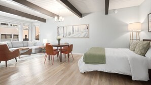 Una moderna camera d'albergo con un letto grande, un'area pranzo con sedie, un divano e un quadro appeso al muro.