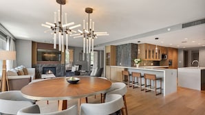 A modern kitchen with a central island, a dining area with a round table, and a living space with a fireplace. - Luxe Resort Penthouse - Ski in Ski Out 3 Bedroom (Snowmass Village)