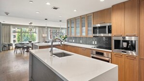 A modern kitchen with wooden cabinets, stainless steel appliances, and a marble countertop. - Luxe Resort Penthouse - Ski in Ski Out 3 Bedroom (Snowmass Village)